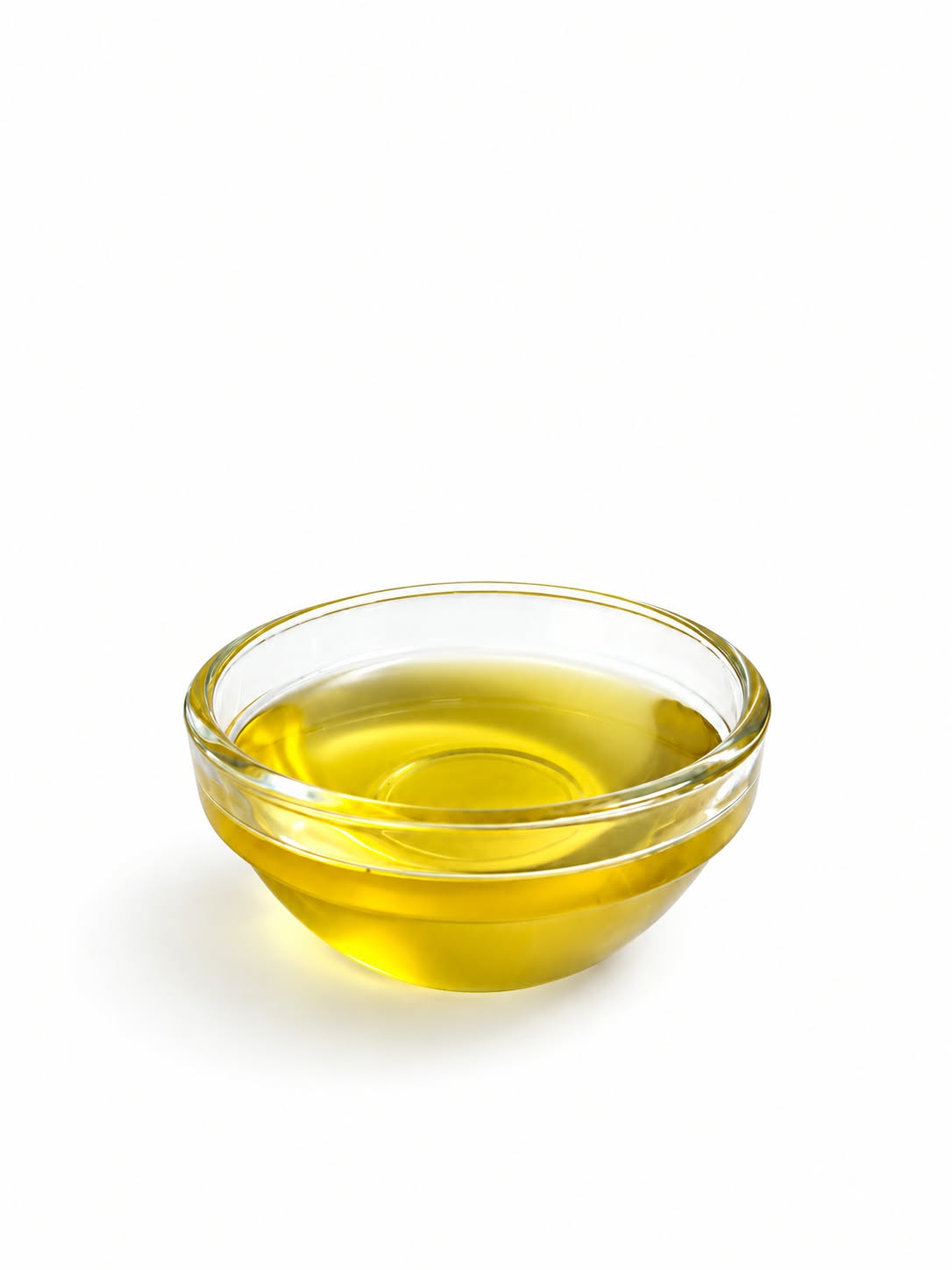 A small clear glass bowl filled with golden yellow oil, photographed on a clean white background.